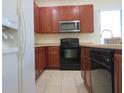 Bright kitchen featuring a black oven and microwave, stainless steel sink, and tiled floors at 318 Habitat Way, Sanford, FL 32773