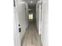 Long hallway featuring wood floors, white doors, and leads to the living room with lots of light at 6937 Se 23 Ave, Ocala, FL 34480