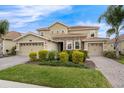 Charming two-story home with a two-car garage, brick driveway, stone accents, and well-manicured landscaping at 8995 Croquet Ct, Champions Gate, FL 33896