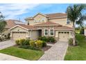 Charming two-story home with a two-car garage, brick driveway, stone accents, and well-manicured landscaping at 8995 Croquet Ct, Champions Gate, FL 33896