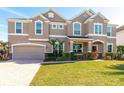 Elegant two-story home with a well-kept lawn, manicured shrubs, brick-paved driveway, and a two-car garage at 15165 Heron Hideaway Cir, Winter Garden, FL 34787
