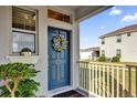 Inviting front porch with a blue door decorated with a wreath and adjacent flowering plants at 15914 Moonlight Bay St, Winter Garden, FL 34787