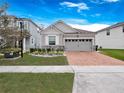 Attractive single-story home with a gray exterior, stone accents, and a brick driveway at 2479 Empress Dr, Kissimmee, FL 34741