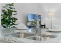 Close up of a stainless steel kitchen sink and modern faucet atop a granite countertop at 3350 Private Oak Dr, Apopka, FL 32703