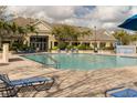 Community pool with blue lounge chairs on a brick patio and a clubhouse in the background at 4008 San Gallo Dr # 102, Kissimmee, FL 34741