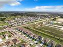 Expansive aerial view of a residential community with lush green spaces, sidewalks, and community pool at 993 Calico Pointe Cir, Groveland, FL 34736