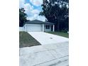New single-story home with a white exterior, an attached garage, and a long concrete driveway at 1015 25Th St, Orlando, FL 32805