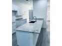 Kitchen island with stainless faucet, granite countertop, white cabinets and gray wood-look tile flooring at 1015 25Th St, Orlando, FL 32805