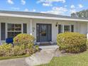 Close up of charming front porch with brick detail, gray shutters, and welcoming front door at 19 Meadowlake Ct, Winter Haven, FL 33884