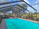 Beautiful screened-in pool with lounge chairs, lush landscaping and view of the golf course at 19 Meadowlake Ct, Winter Haven, FL 33884