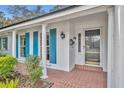 Close up of the home's front door with brick flooring, white pillars and blue shutters on the front windows at 2642 Tierra Cir, Winter Park, FL 32792