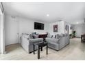 Cozy living room with matching sofas, a wall-mounted TV, and neutral-toned tile flooring at 411 Ridges Dr, Dundee, FL 33838