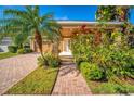 Charming single-story home featuring a brick walkway, attached garage, and colorful tropical landscaping at 7736 Brofield Ave, Windermere, FL 34786