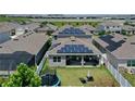 Aerial view of a backyard with solar panels, a trampoline, seating, and a white fence at 9180 Carmela Ave, Davenport, FL 33897