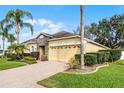 Side view of a single-story home with a two-car garage, brick driveway, and well-maintained landscaping at 9848 Nonacrest Dr, Orlando, FL 32832