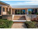 Exterior shot features a metal roof, stone steps, and tidy landscaping for great curb appeal at 12104 Lakeshore Dr, Clermont, FL 34711