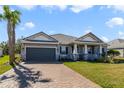 Inviting single-story home showcasing a brick driveway, lush lawn, and covered front porch at 1324 Arklow Cir, Ormond Beach, FL 32174