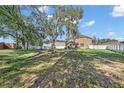 Expansive backyard showcasing mature trees, lush green grass, and a secure white vinyl fence at 1465 Osprey Ridge Dr, Eustis, FL 32736