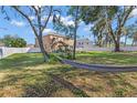 Spacious backyard featuring lush green grass, mature trees, a hammock, and a white vinyl fence at 1465 Osprey Ridge Dr, Eustis, FL 32736