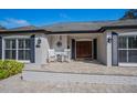 Close up of front entrance features double wood doors, two rocking chairs on brick tile, address, and round window at 1591 Chippewa Trl, Maitland, FL 32751