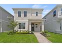 A bright two-story home showcases lush landscaping and a brick walkway leading to a covered porch at 2026 Education St, St Cloud, FL 34771