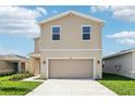 Tan two-story home with a two-car garage, a well-manicured lawn, and a concrete driveway at 3507 Salvia Ct, Tavares, FL 32778