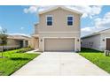 Tan two-story home with a two-car garage, a well-manicured lawn, and a concrete driveway at 3507 Salvia Ct, Tavares, FL 32778