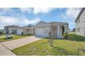 Inviting front exterior of home featuring a lush lawn, and wide driveway at 863 August Sky Dr, Deltona, FL 32738