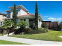 Two-story home with tile roof, manicured landscaping, and walkway to front entrance at 9406 Mere Pkwy, Orlando, FL 32832