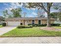 Home with stone accents, a green lawn, mature tree, and a two-car garage at 1026 Woodall Dr, Altamonte Springs, FL 32714