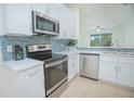 Bright kitchen with stainless steel appliances, tiled backsplash, and white cabinetry at 1660 Mountclair Ct, Mount Dora, FL 32757