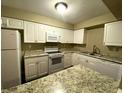 Bright kitchen features white cabinets, granite countertops, and updated stainless steel appliances at 516 Orange Dr # 17, Altamonte Springs, FL 32701