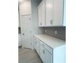 Kitchen showcasing white cabinets, quartz countertops, and stylish gray backsplash tiles, next to a white pantry door at 5961 Vision Rd, St Cloud, FL 34771