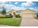 Charming single-story home featuring a manicured lawn, stone accents, and a brick driveway at 636 Bainbridge Loop, Winter Garden, FL 34787