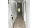 Bright hallway showcasing wood-look flooring, white walls and trim, leading to a sunlit living area at 6889 Se 23 Ave, Ocala, FL 34480