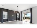 Open living space featuring a decorative chandelier, grey-toned accent wall, tile floors, and sliding glass doors to the yard at 16112 Vetta Dr, Montverde, FL 34756