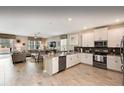 Open-concept kitchen with white cabinets, stainless steel appliances, and an island with seating flows into a cozy living area at 1656 Moon Valley Dr, Davenport, FL 33896