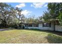 Quaint single-story home with mature trees providing shade and curb appeal, complemented by a well-maintained front lawn at 2108 Kilmer Ln, Apopka, FL 32703