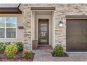 Elegant entryway with stone detailing, modern door, and manicured landscaping at 4164 Paragraph Dr, Kissimmee, FL 34746