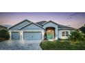 Charming one-story home boasts a three-car garage and inviting light-blue front door, set against a twilight sky at 6148 Gracie Pl, Lakeland, FL 33812