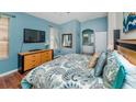 Cozy bedroom with blue walls, wood floors, tv, ensuite bath, and comfortable patterned bedding at 8157 Fan Palm Way, Kissimmee, FL 34747