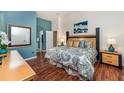 Comfortable main bedroom featuring wood floors, ensuite bath, and a beautiful accent painting at 8157 Fan Palm Way, Kissimmee, FL 34747