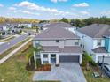Aerial view of a gray two-story home in a residential neighborhood with well-maintained lawns and paved streets at 178 Marcello Blvd, Kissimmee, FL 34746