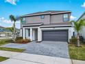 Charming two-story gray home with a two-car garage, palm trees, and a paved driveway on a sunny day at 178 Marcello Blvd, Kissimmee, FL 34746