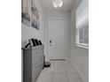 Bright entryway featuring neutral tile floors, a gray shoe cabinet, and a white front door at 2916 Satire St, Kissimmee, FL 34746