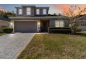 Charming two-story home with well-manicured lawn and a brick driveway at sunset at 34429 Alameda Dr, Sorrento, FL 32776