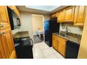 Kitchen with wood cabinets, black appliances, granite countertops, and tile flooring at 4759 S Texas Ave # 4759C, Orlando, FL 32839