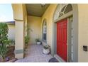 Charming front porch features tiled flooring, potted plants, and a vibrant red front door at 11554 Blackmoor Dr, Orlando, FL 32837