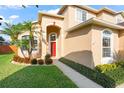 Attractive home exterior featuring a vibrant red door, lush landscaping, and well-maintained lawn at 1243 Osprey Way, Apopka, FL 32712