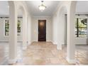 Elegant foyer featuring arched entryways, a dark wood front door, neutral paint and travertine tile flooring at 1690 Oneco Ave, Winter Park, FL 32789